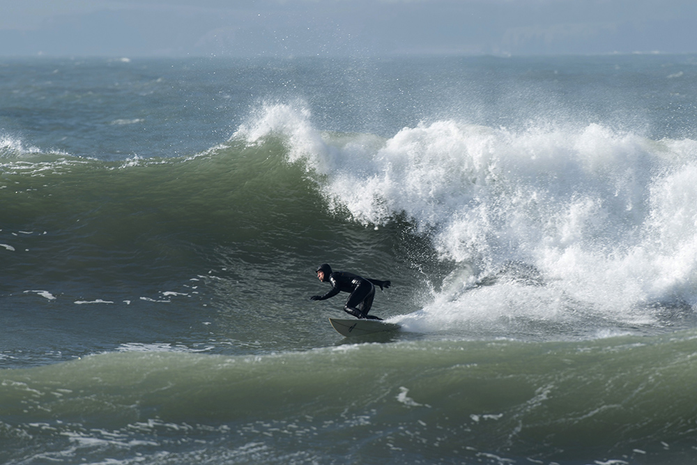 surfer bottom turning at base of huge wave