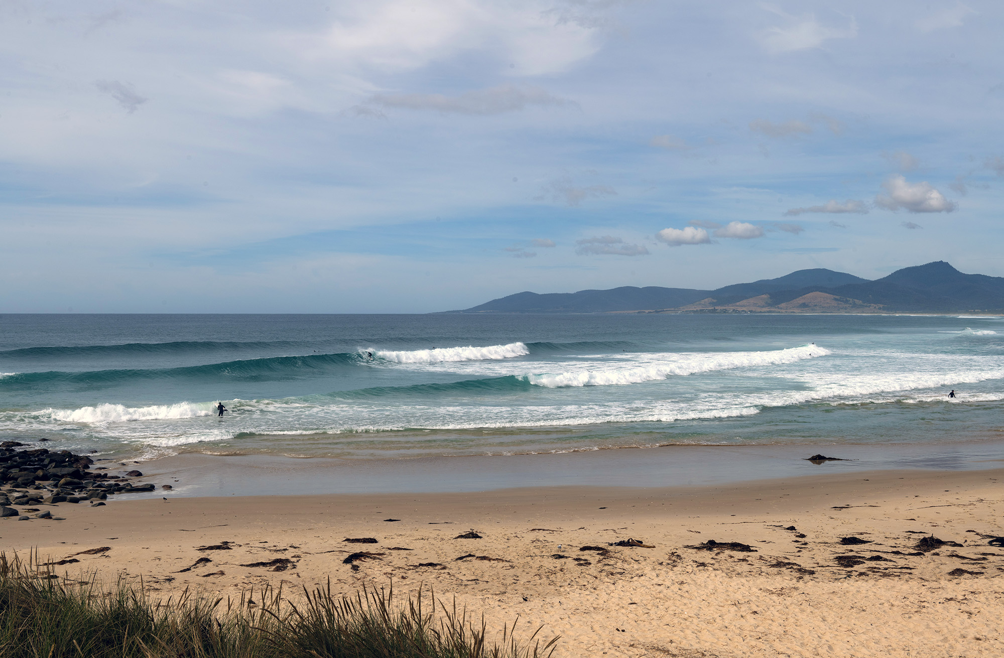 A beautiful bay with perfect beach break , distant hills on horizon